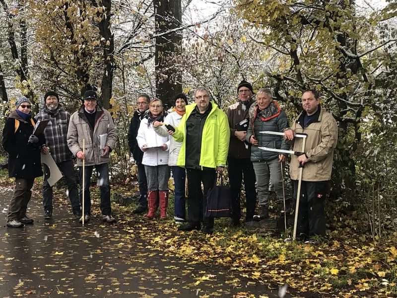 Gruppe der Bürgerinitiative mit Maßbändern und Notizen auf dem herbstlichen Gelände unter Bäumen
