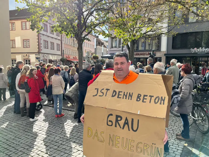 Ein Demonstrant hält ein Pappschild: Ist denn Beton grau das neue Grün?