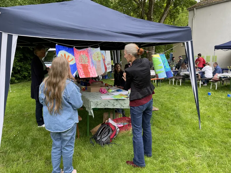 Kinder malen an einem Stand unter einem Pavillon